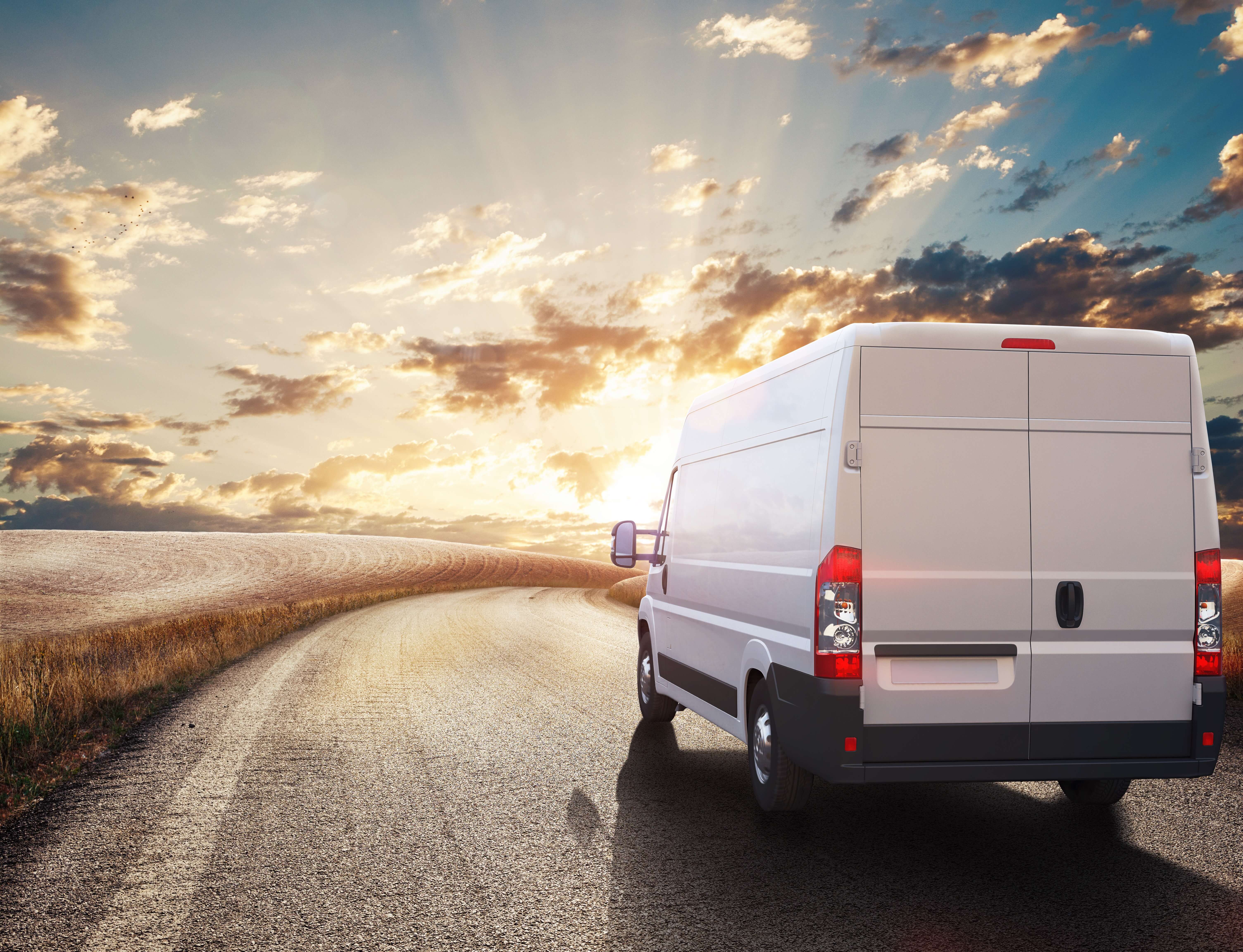 A light commercial vehicle drives into the sunset on a tar road