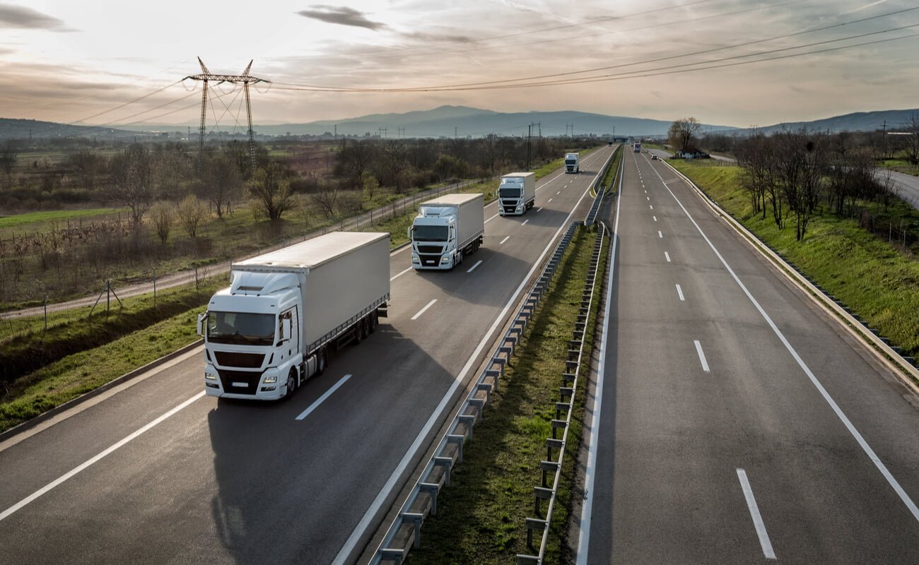 A fleet of trucks driving down a country road